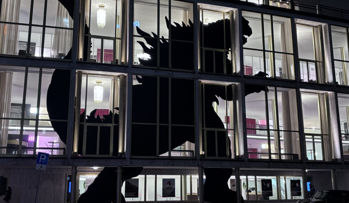 Silhouette of godzilla against illuminated windows